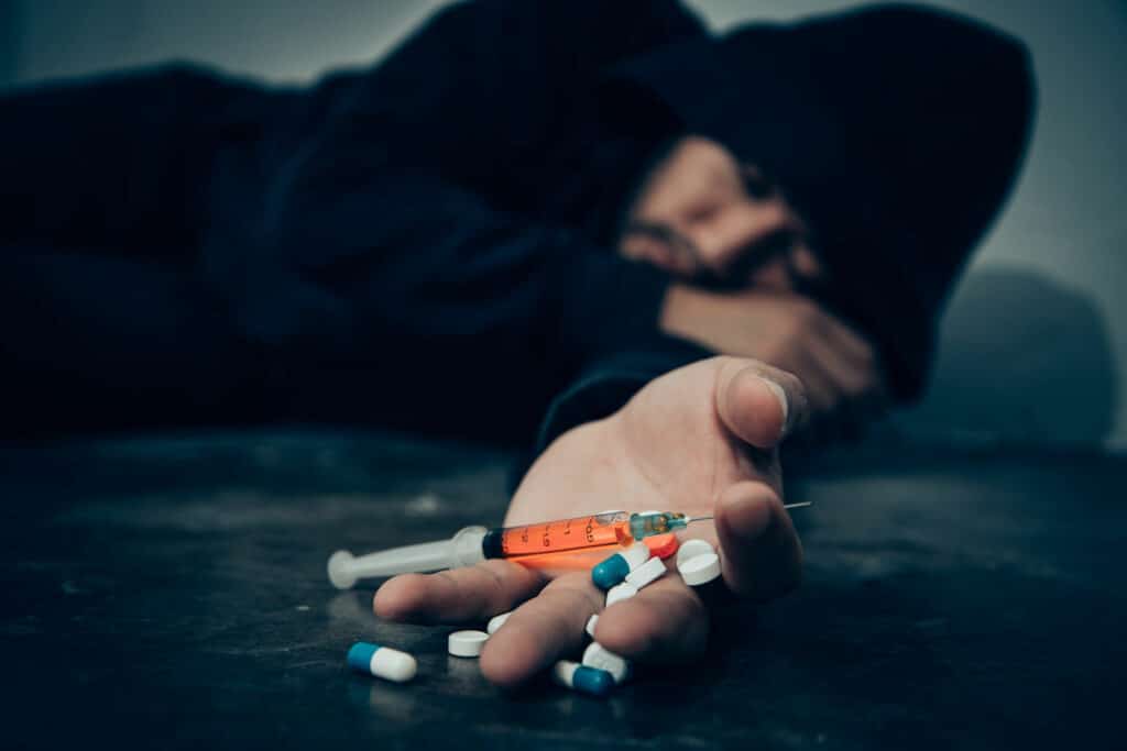 man-lying-on-the-floor-with-pills-and-syringe-on-hand-1-1 || صحةسكاي